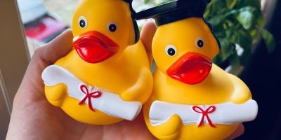 Two yellow rubber ducks with graduation caps and rolled up diplomas